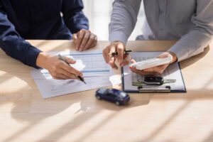 A person reviews insurance documents and medical bills at a kitchen table with a calculator and paperwork.